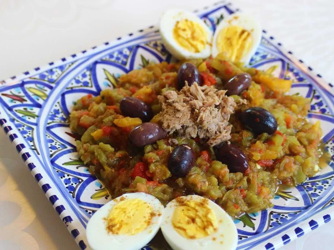 Salade mechouia au thon, olives et œufs durs, servie dans un plat en faïence de Nabeul